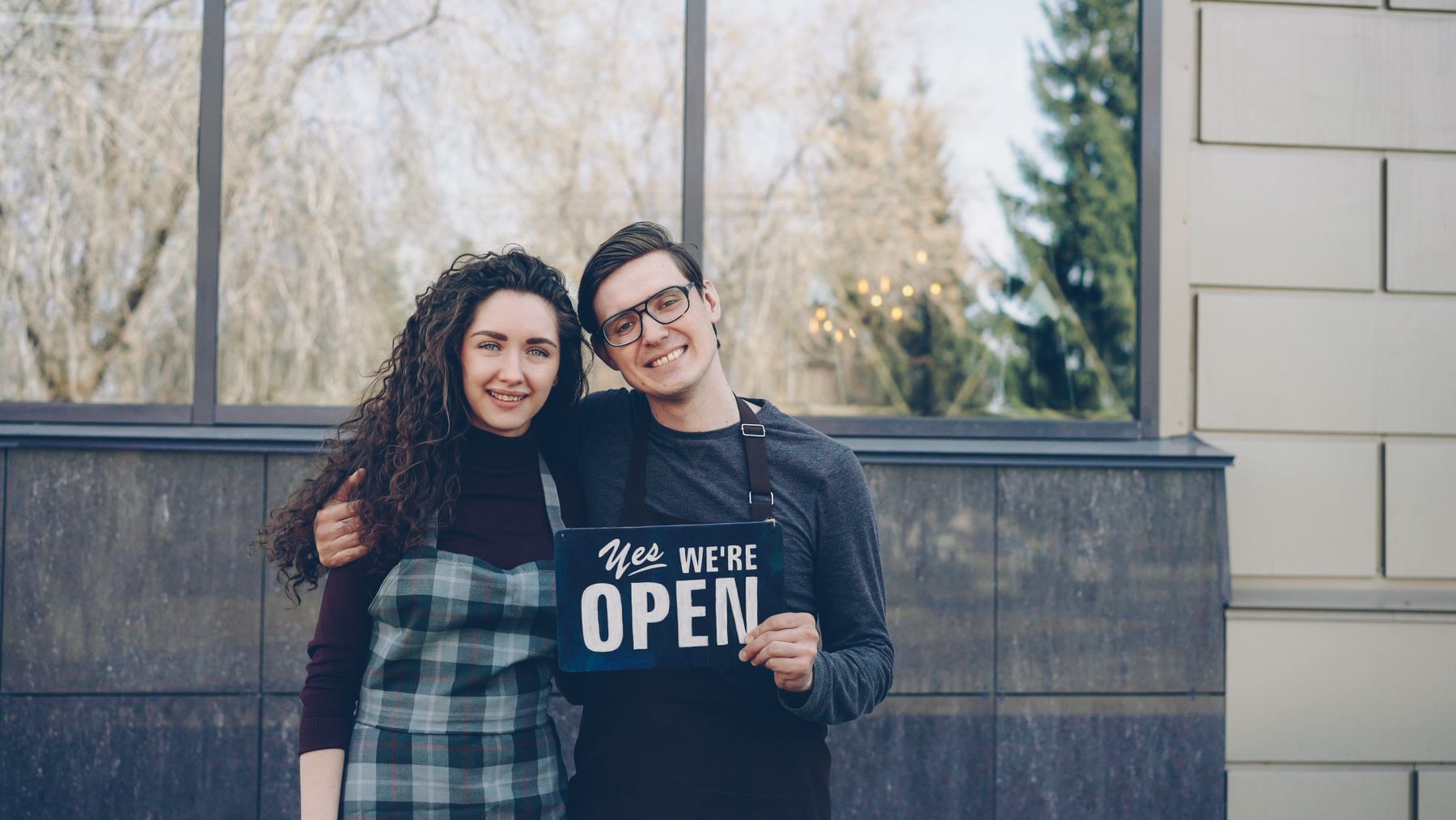 Two friendly fictional local business owners outside a storefront