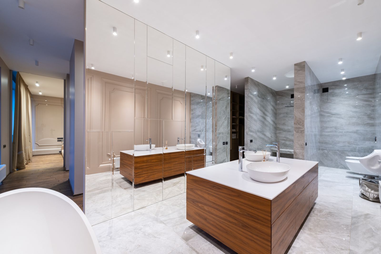 Modern primary bathroom with wood vanities and gray stone