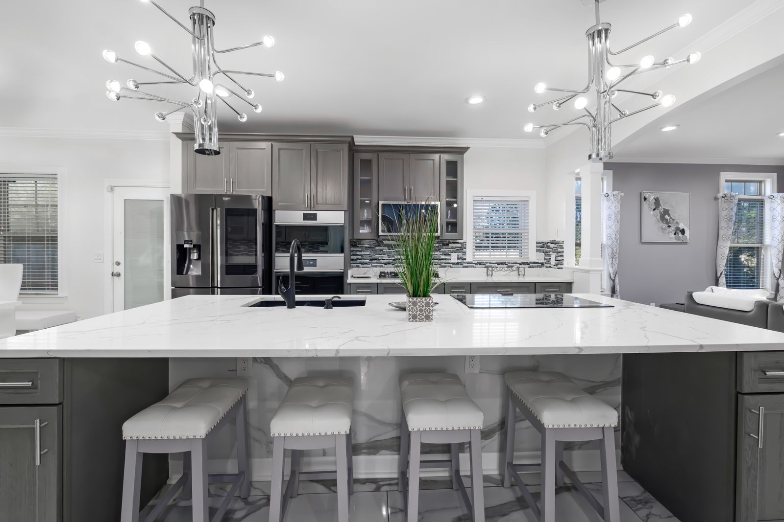 Bright remodeled kitchen with a large marble island and gray cabinetry